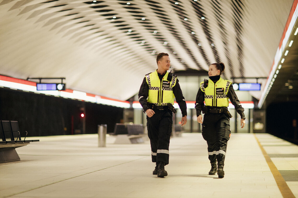 Kaksi järjestyksenvalvojaa kävelee metrolaiturilla